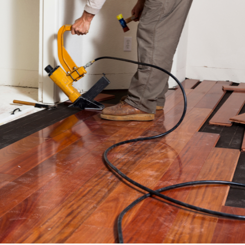 A man professionally install flooring in the house.